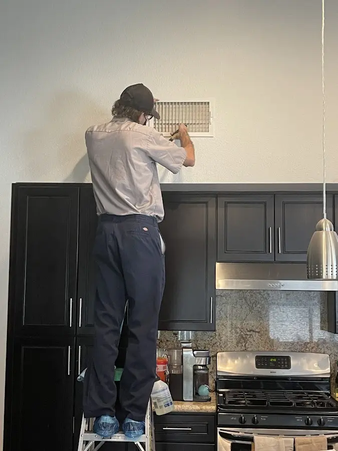 Technician inspecting an air vent during HVAC service in Fort Walton Beach